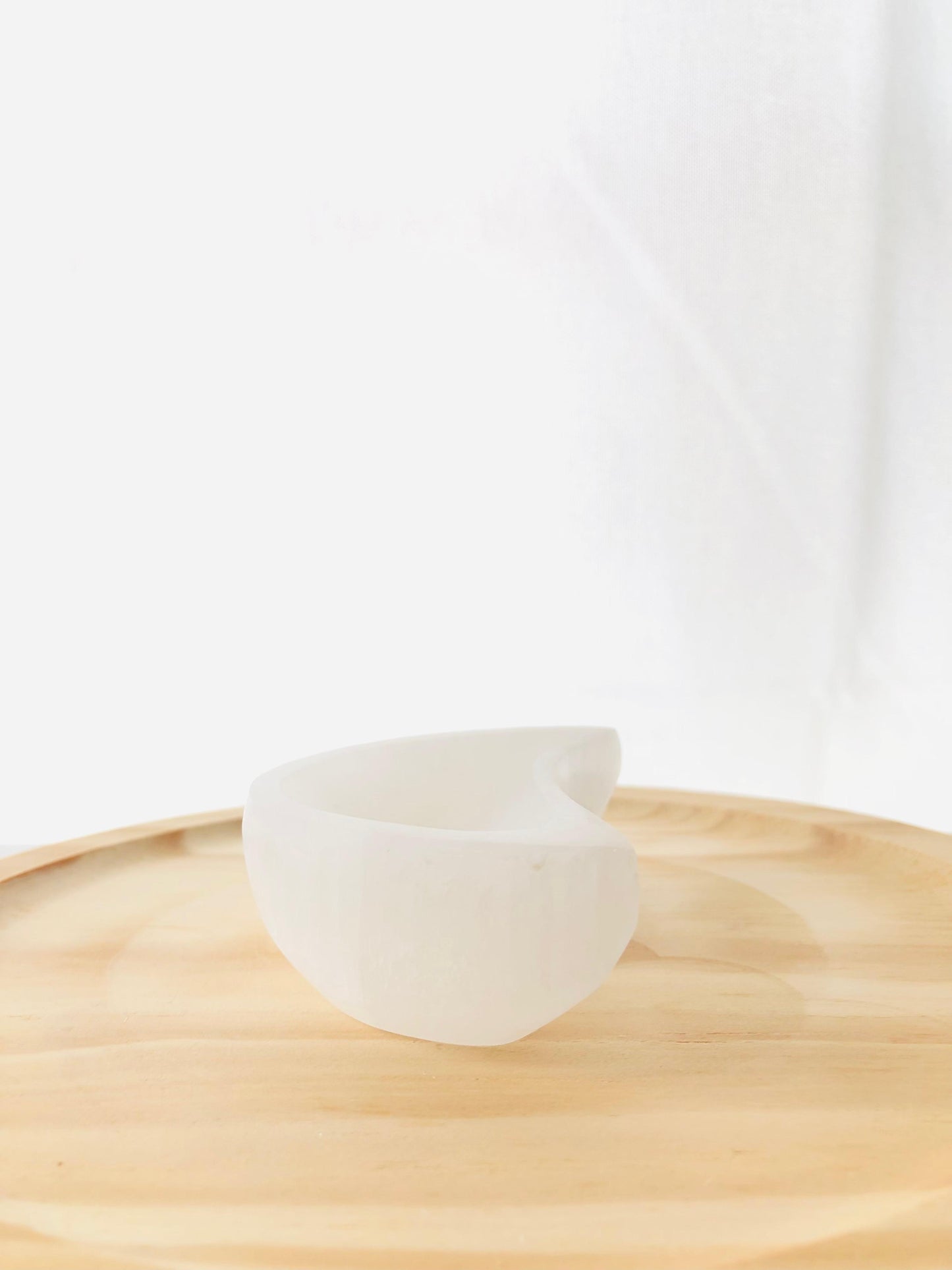 Cuenco artesanal tallado en selenita natural con forma de media luna blanca, ideal para decorar mesitas de noche o espacios de meditación.