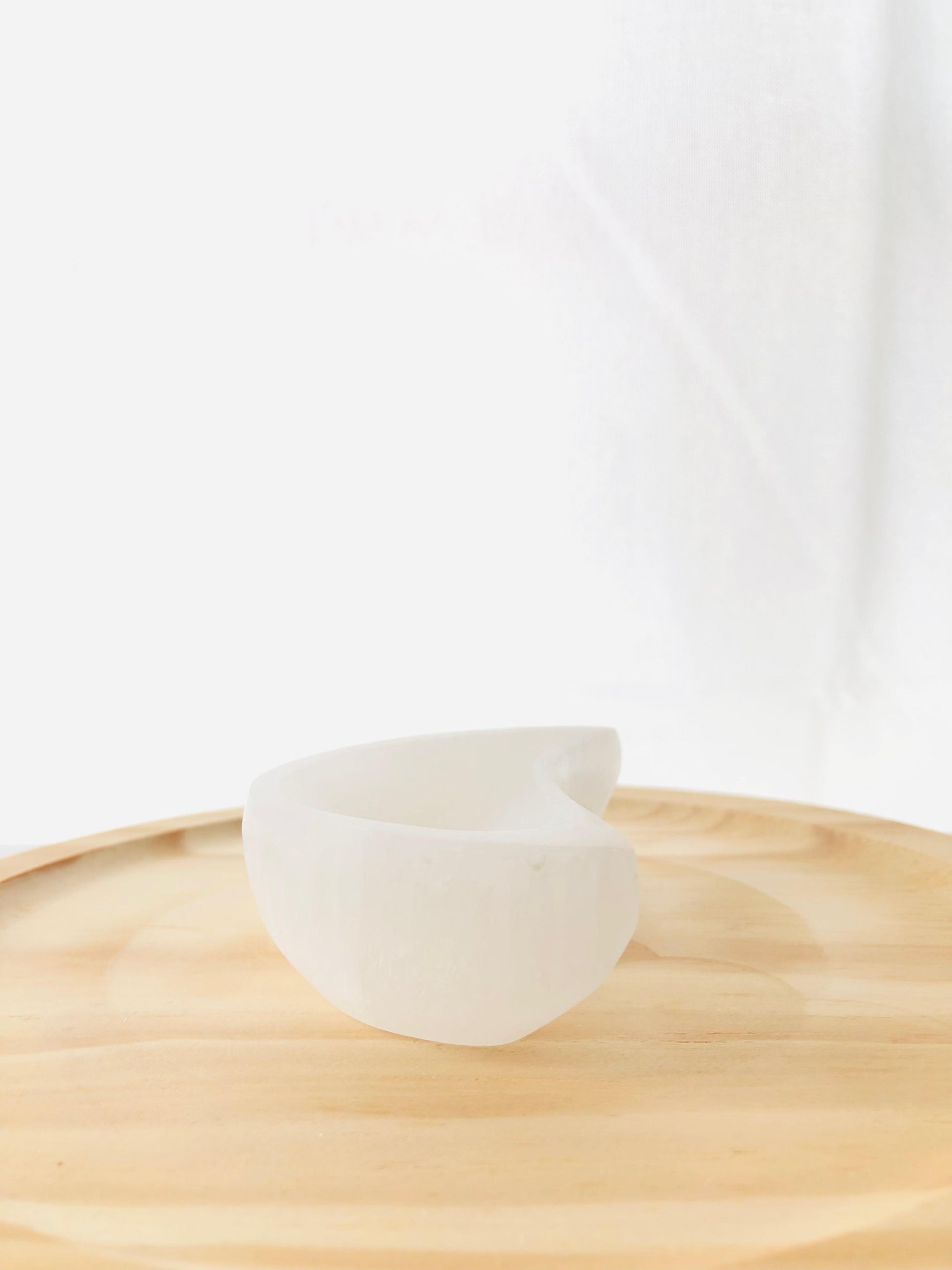 Cuenco artesanal tallado en selenita natural con forma de media luna blanca, ideal para decorar mesitas de noche o espacios de meditación.