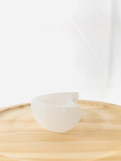 Cuenco artesanal tallado en selenita natural con forma de media luna blanca, ideal para decorar mesitas de noche o espacios de meditación.