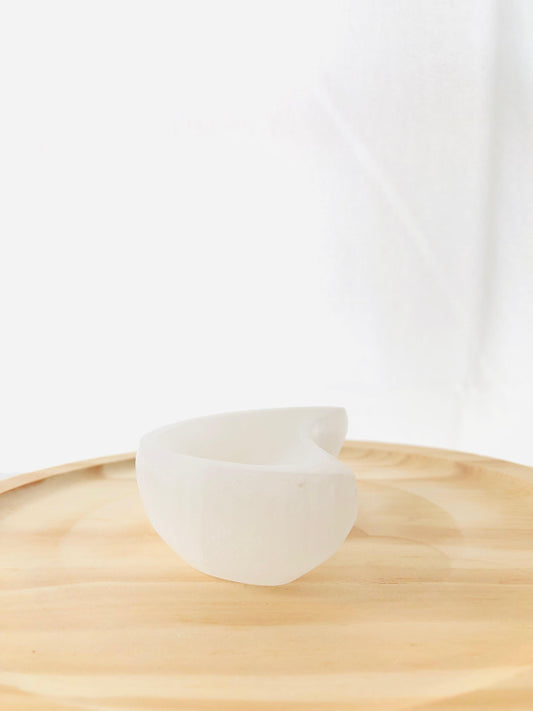 Cuenco artesanal tallado en selenita natural con forma de media luna blanca, ideal para decorar mesitas de noche o espacios de meditación.