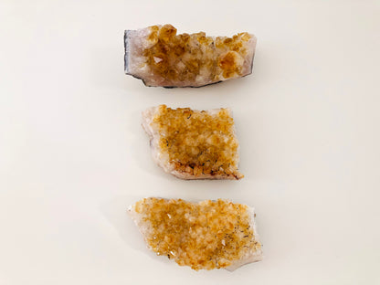 Set de tres piedras de citrino en bruto tipo drusa mostrando su estructura cristalina natural.