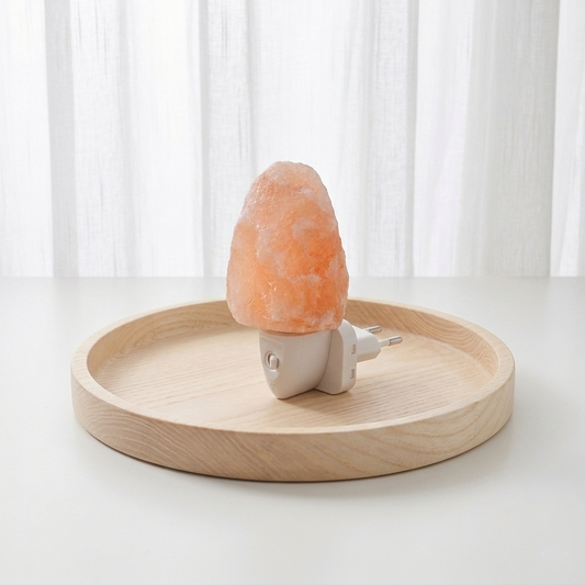 Lámpara de sal del Himalaya tallada en forma natural sobre una base de madera, emitiendo una luz cálida y tenue de color naranja suave en una habitación oscura.
