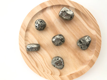 piedras de pirita en formato rodado, de superficie lisa y reflejos metálicos similares al oro.