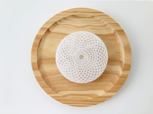 Base circular de selenita natural con grabado de geometría sagrada para limpieza y carga de cristales y joyería.