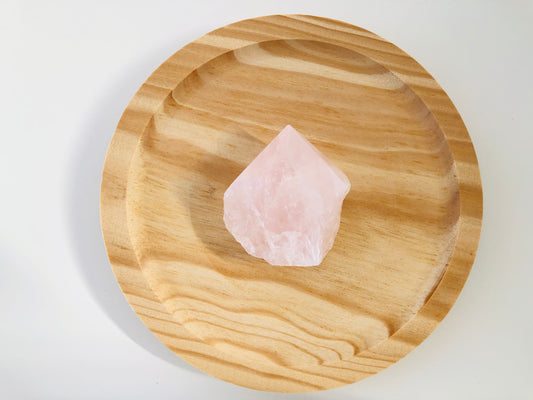 Pieza de cuarzo rosa natural con la base en estado bruto y rugoso, mientras que la parte superior presenta un acabado semipulido liso y brillante de color rosa suave.