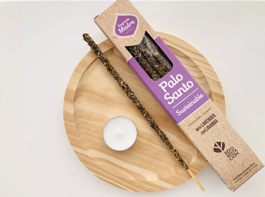 Caja de inciensos naturales Sagrada Madre de Palo Santo y Lavanda, mostrando varillas de biomasa artesanal con flores de lavanda visibles y textura porosa de color lila suave y marrón.