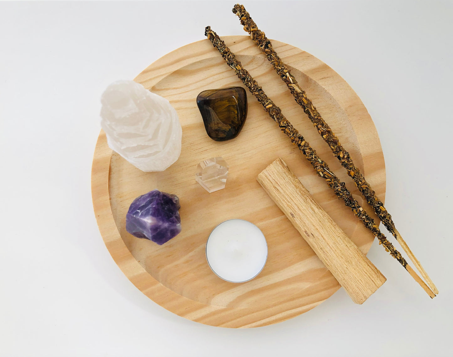 Set de protección espiritual con un monolito de selenita blanca en forma de torre, una piedra amatista violeta natural y un ramillete de varas de palo santo atadas con hilo.