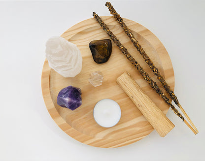 Set de protección espiritual con un monolito de selenita blanca en forma de torre, una piedra amatista violeta natural y un ramillete de varas de palo santo atadas con hilo.