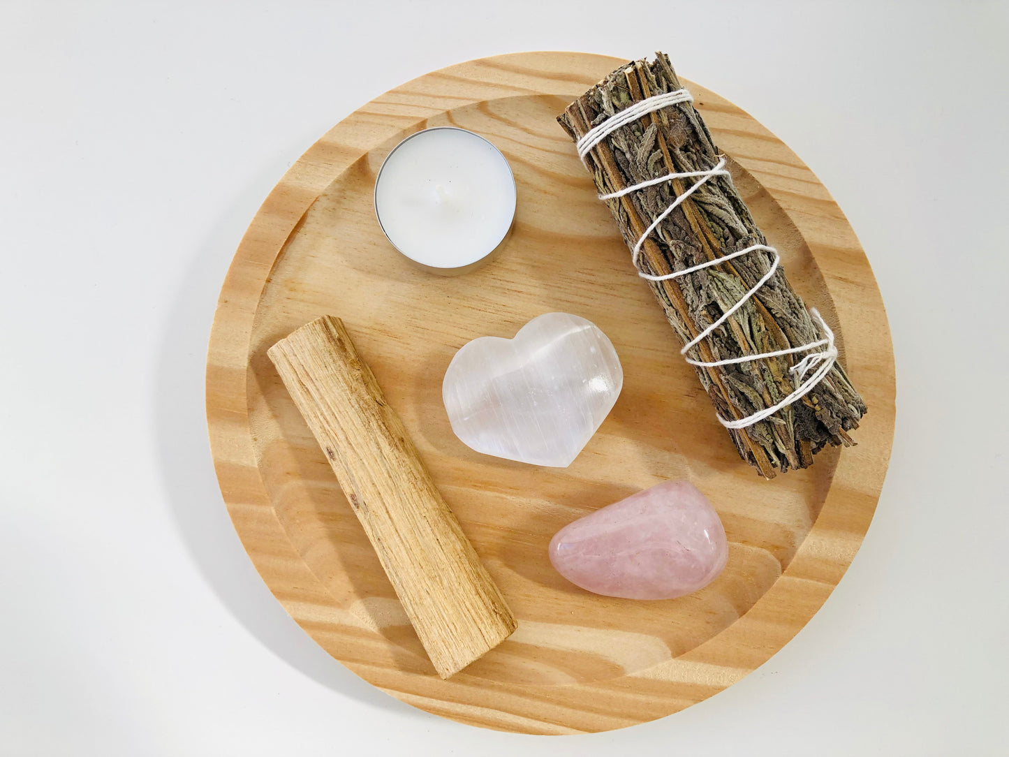 Set de ritual 'Amor Propio' que incluye un cuarzo rosa pulido, elementos para sahumado natural y accesorios de bienestar, dispuestos armoniosamente en una caja de presentación.