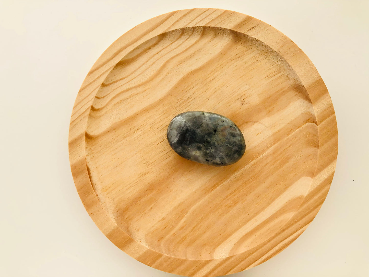 Pequeño canto rodado de labradorita pulida de tamaño bolsillo, con una superficie lisa y ovalada que muestra destellos metálicos azules y verdes al girarla.