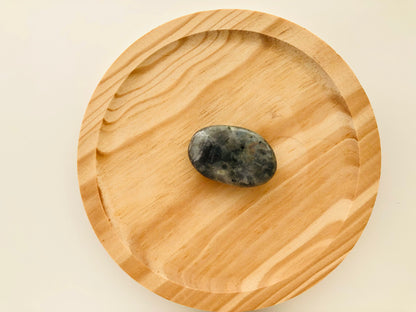 Pequeño canto rodado de labradorita pulida de tamaño bolsillo, con una superficie lisa y ovalada que muestra destellos metálicos azules y verdes al girarla.