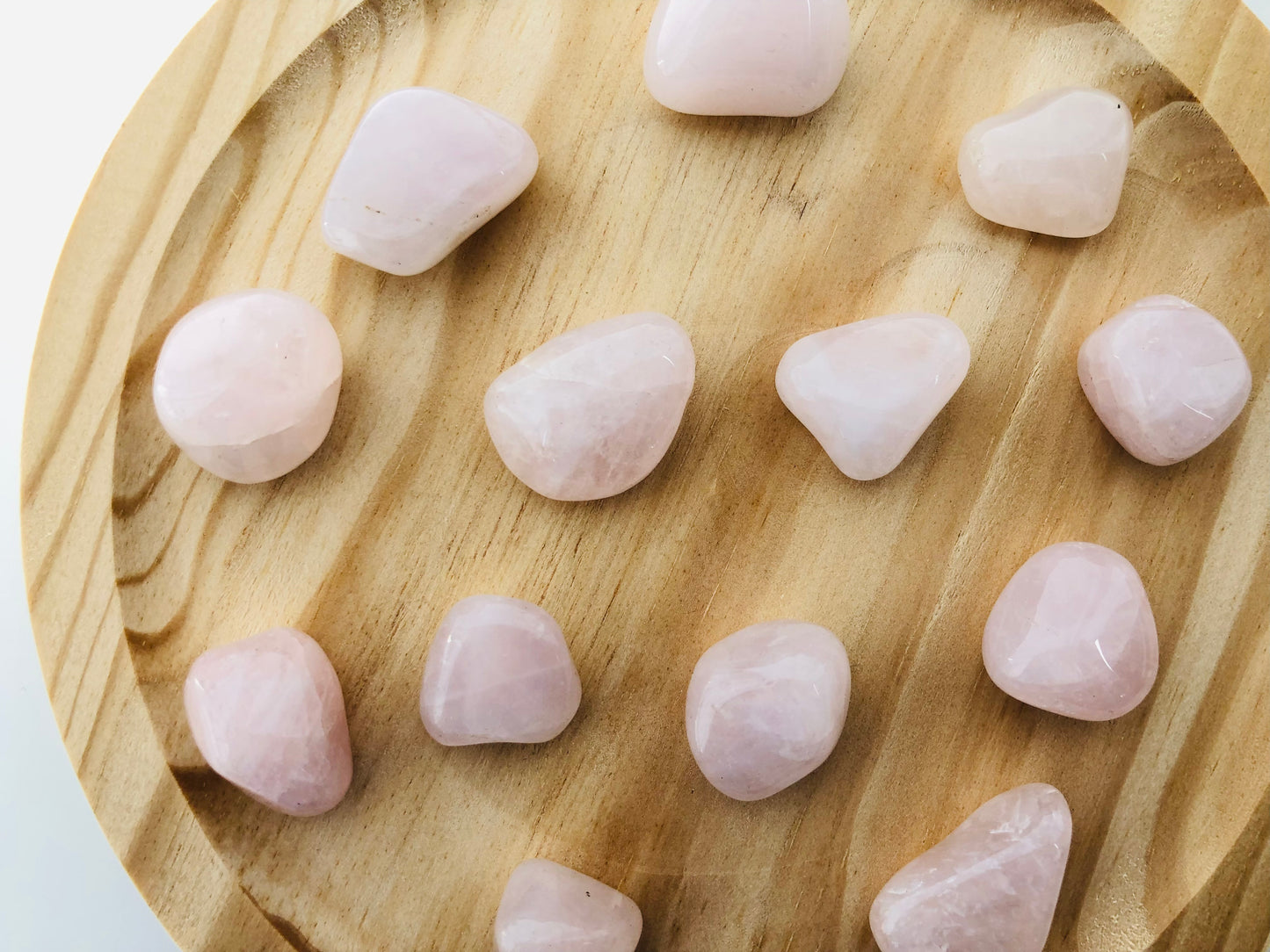Piedra de cuarzo rosa rodado con acabado suave y brillante, mostrando tonos rosados naturales y vetas ligeras sobre un fondo neutro