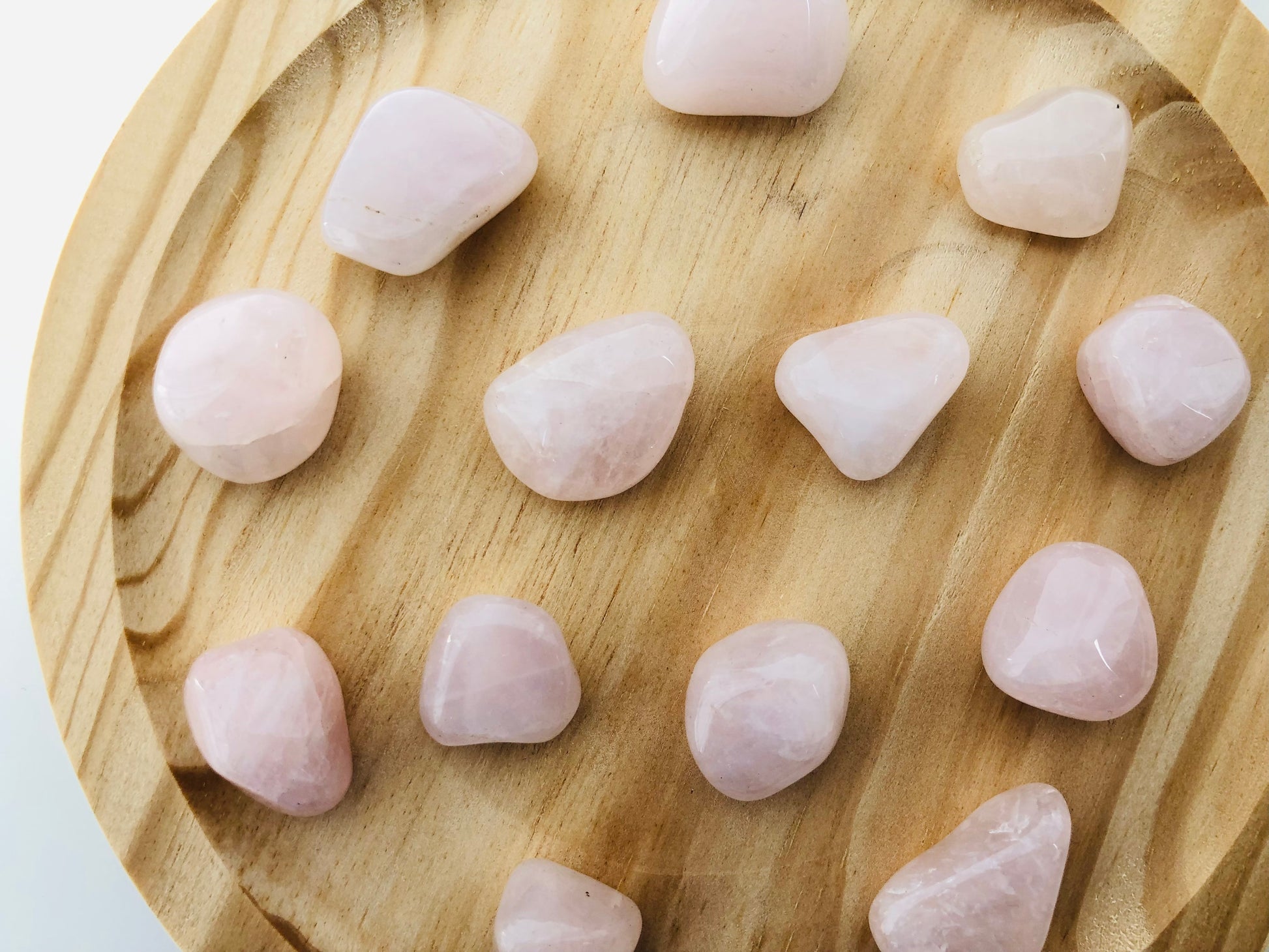 Piedra de cuarzo rosa rodado con acabado suave y brillante, mostrando tonos rosados naturales y vetas ligeras sobre un fondo neutro