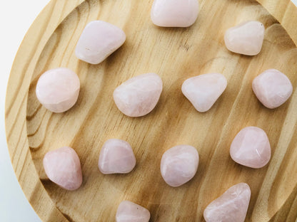 Piedra de cuarzo rosa rodado con acabado suave y brillante, mostrando tonos rosados naturales y vetas ligeras sobre un fondo neutro