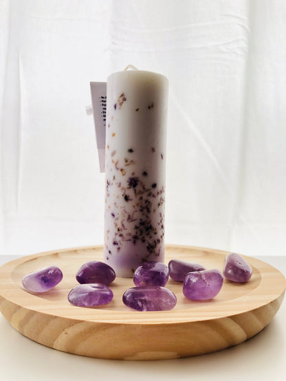 Primer plano de una vela artesanal con drusas de amatista incrustadas, utilizada en rituales esotéricos para transmutar energías y limpiar el aura.
